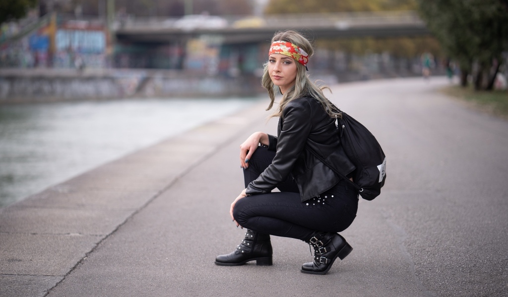 Девушка в черном костюме сидит на корточках