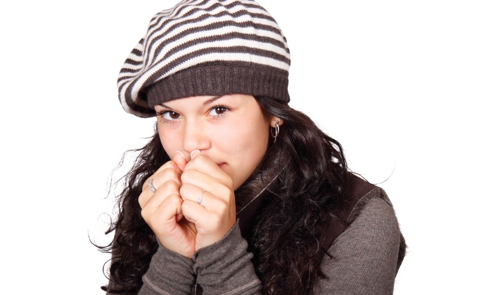 Девушка в теплой полосатой шапке на белом фоне