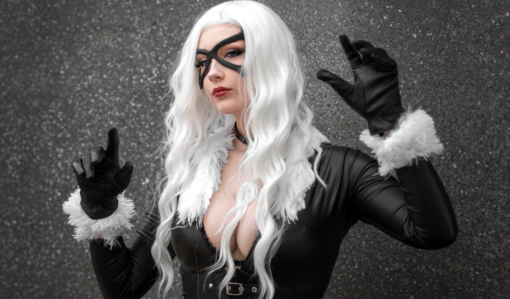 Девушка в белом парике в черном костюме у серой стены