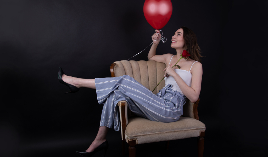 Девушка с шариком и розой сидит в кресле