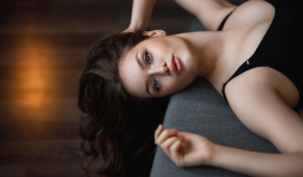 Девушка с длинными волосами лежит  на кровати