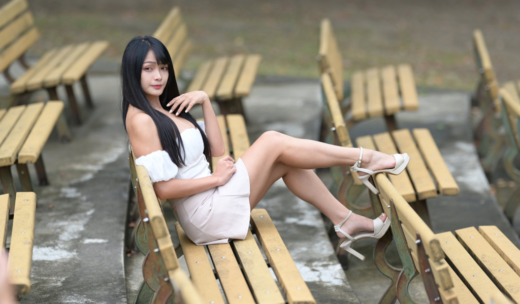 Длинноволосая азиатка сидит на деревянной лавке