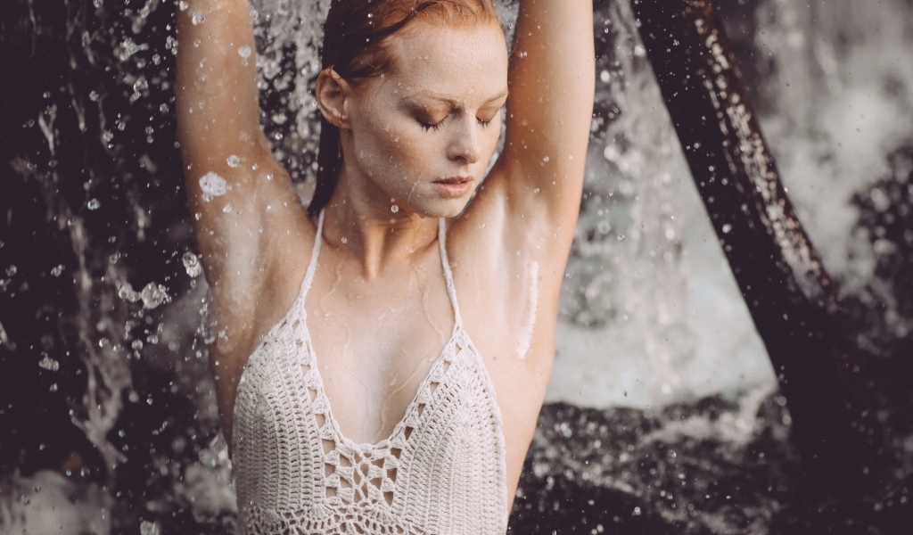 Рыжеволосая девушка в брызгах воды