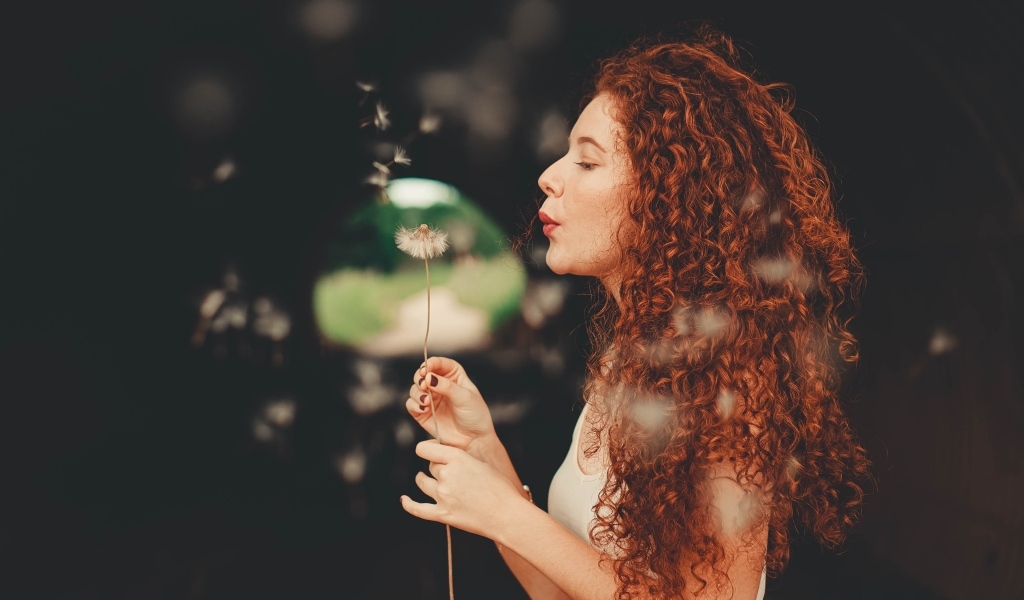 Рыжеволосая девушка с одуванчиком в руке