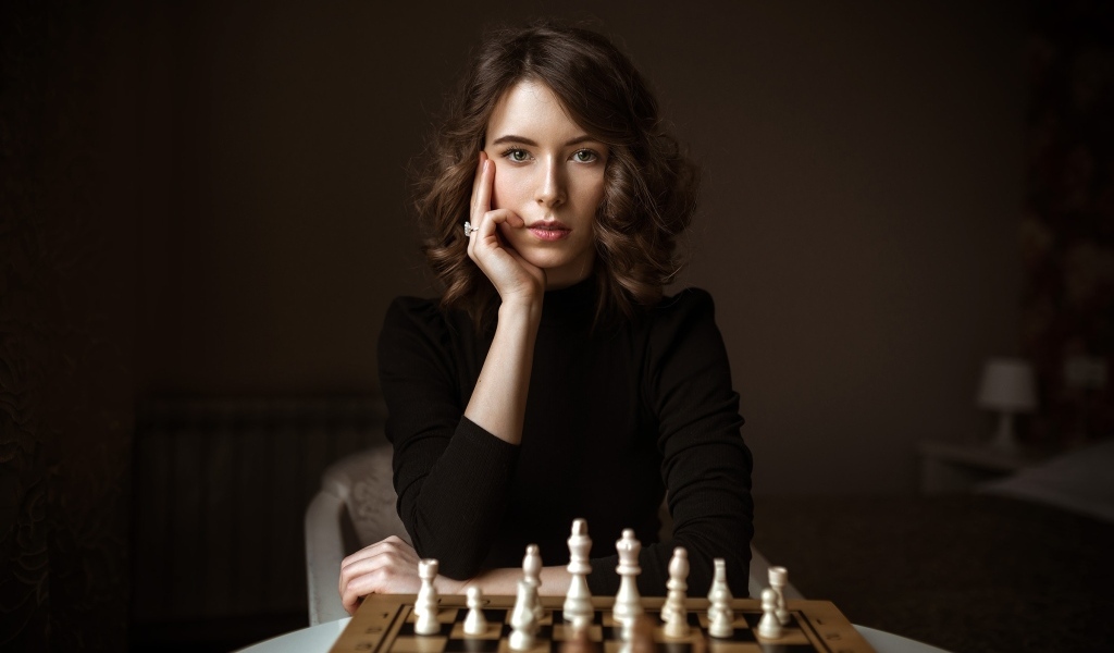 Умная молодая девушка играет в шахматы