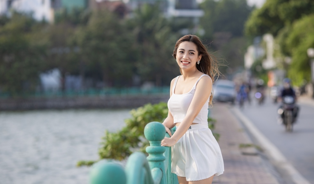 Улыбающаяся девушка азиатка в белом летнем костюме