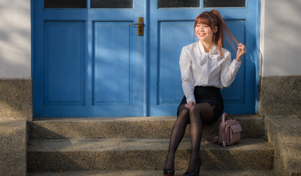 Улыбающаяся азиатка сидит на ступеньках