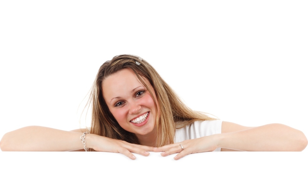 Улыбающаяся девушка сидит на белом фоне