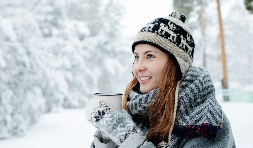 Улыбающаяся девушка с чашкой кофе зимой