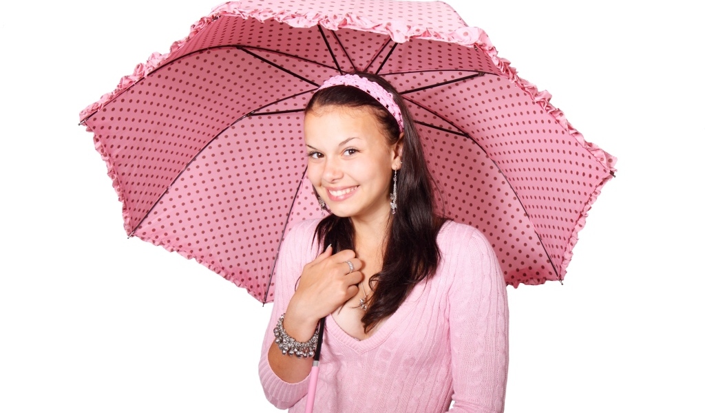 Улыбающаяся девушка с розовым зонтом на белом фоне