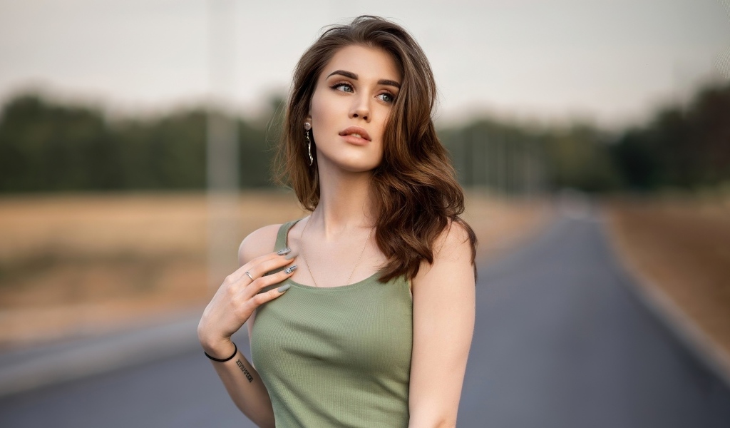 Нежная длинноволосая девушка стоит на дороге