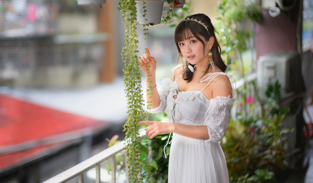 Молодая азиатка в белом платье у растений