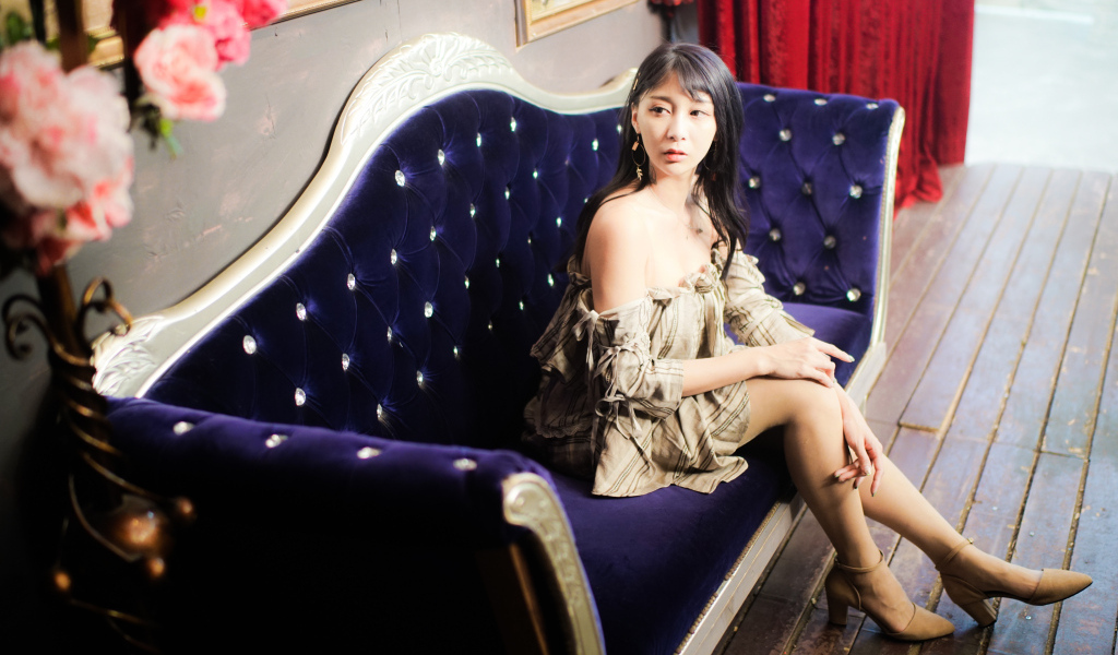 Молодая азиатка сидит на красивом диване