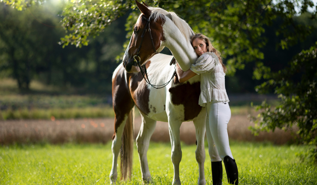 Молодая девушка обнимает большого коня