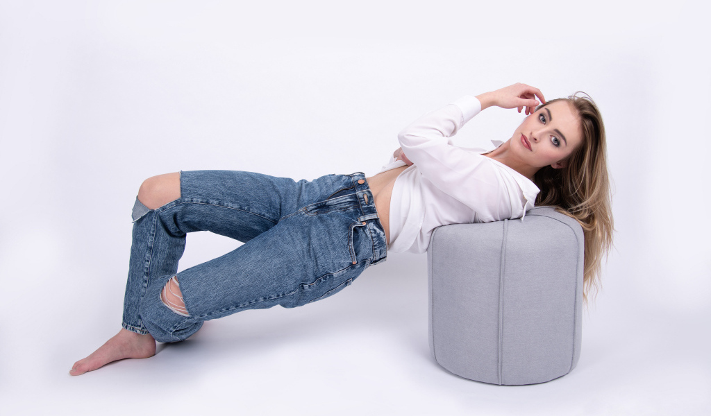 Молодая девушка в джинсах на белом фоне