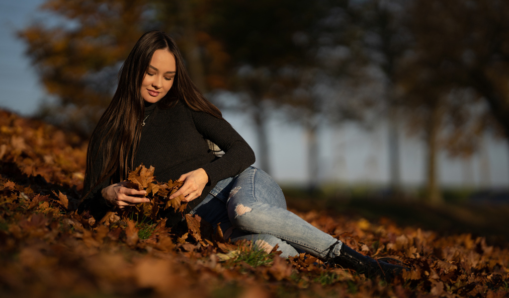 Молодая девушка лежит на сухих опавших листьях