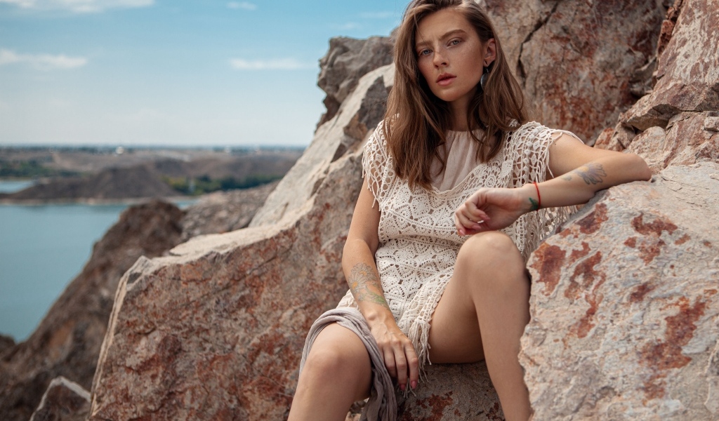 Молодая девушка сидит на камнях