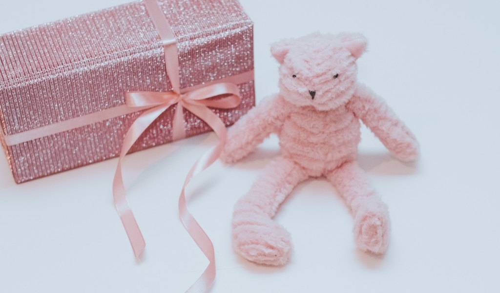 Подарок с розовой игрушкой на сером фоне