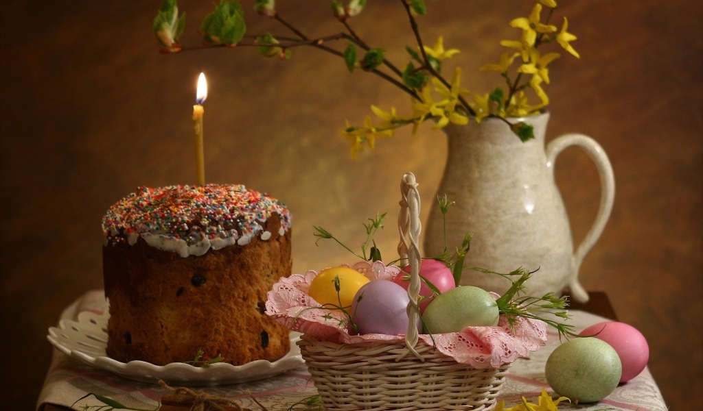 Кулич со свечой и крашеными яйцами на столе на Пасху