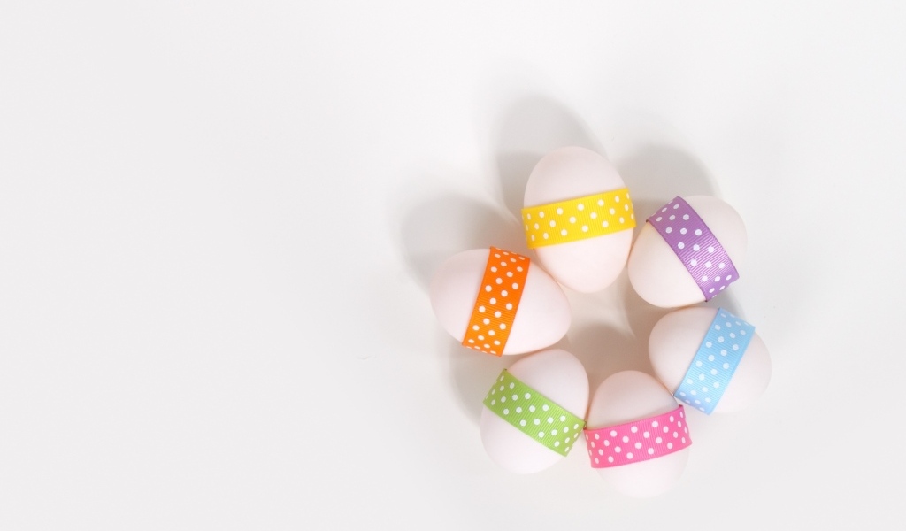 Белые яйца с ленточками на белом фоне