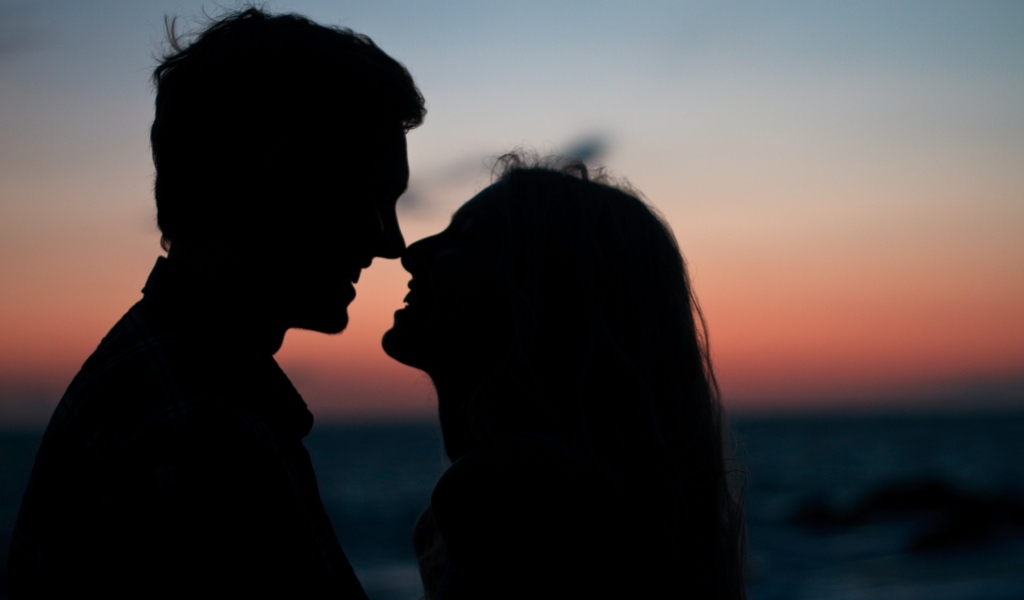 Влюбленная пара стоит на фоне заката в сумерках