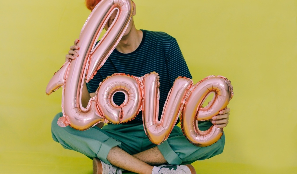 Мужчина держит шарики с надписью любовь