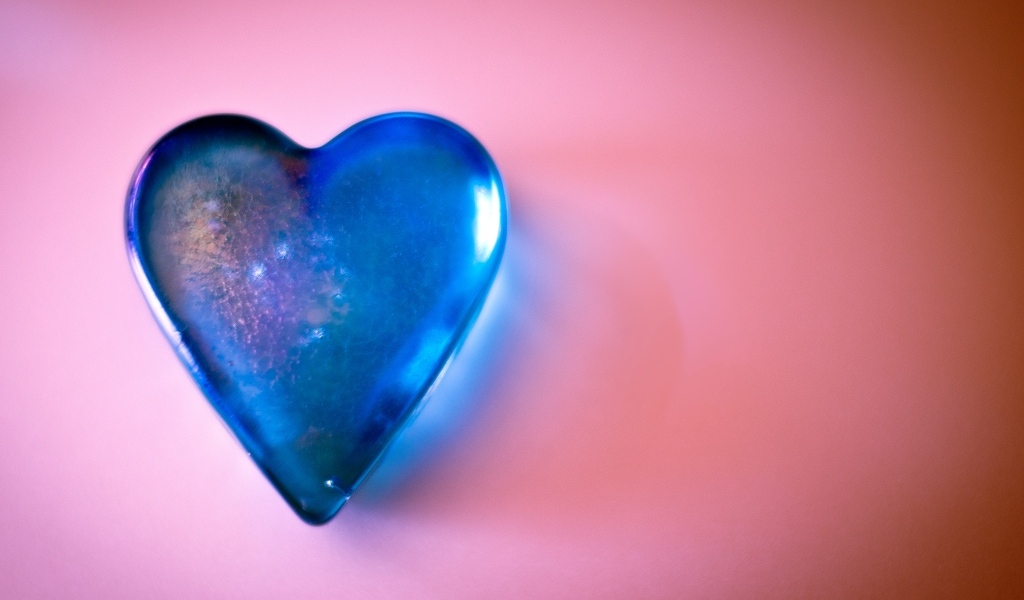 Синее стеклянное сердце на розовом столе