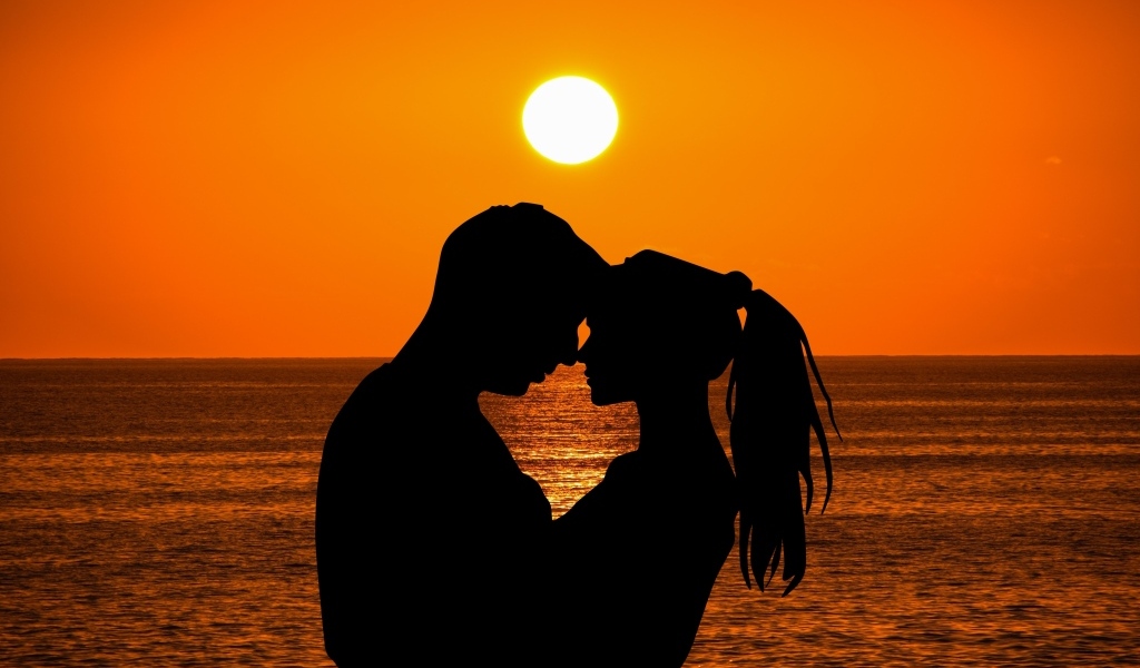Влюбленная пара на закате солнца у моря