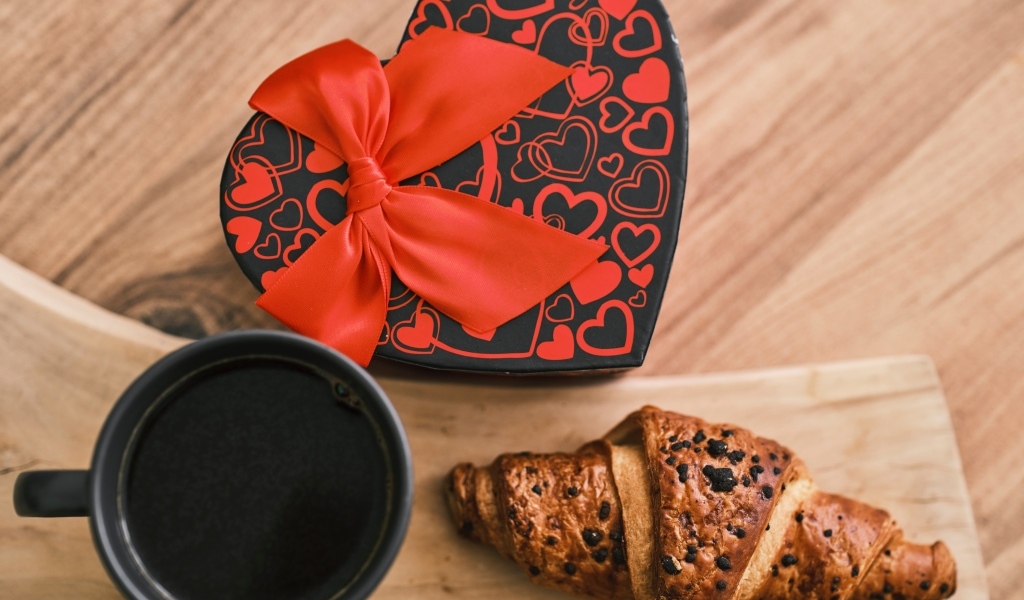 Коробка в форме сердца, кофе и круассан на столе