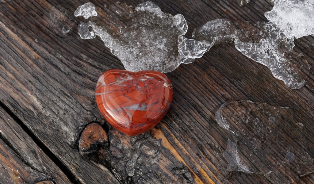 Сердце из камня на деревянной лавке с тающим снегом