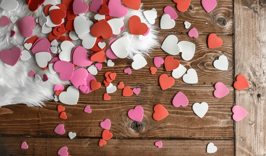 Много бумажных сердечек на деревянном полу
