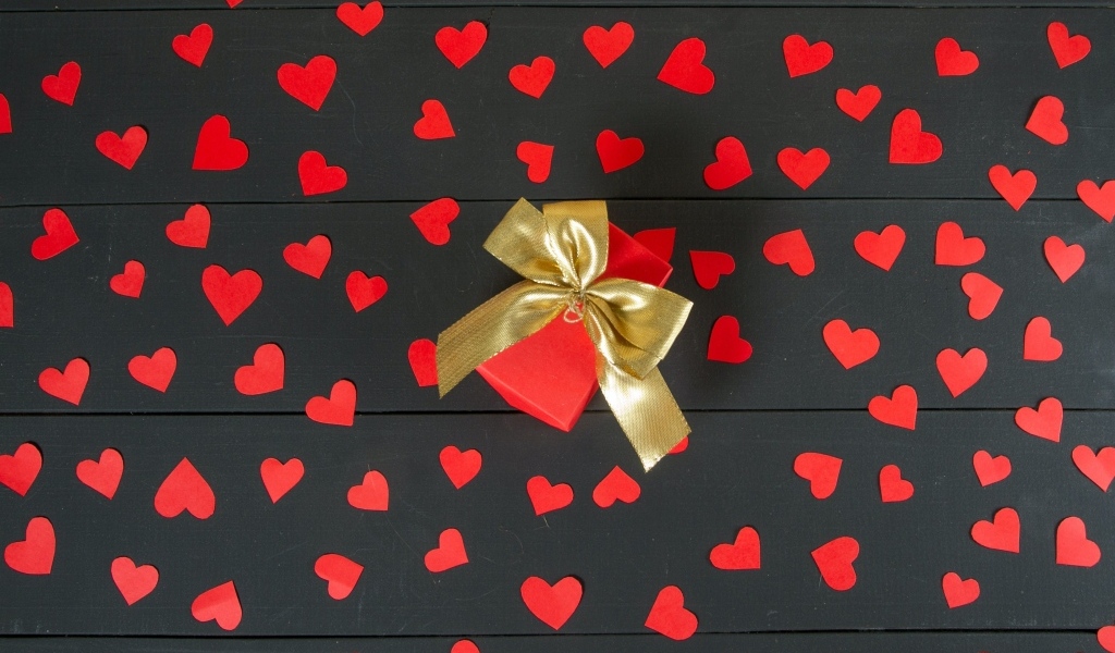 Много маленьких бумажных сердечек с подарком на столе