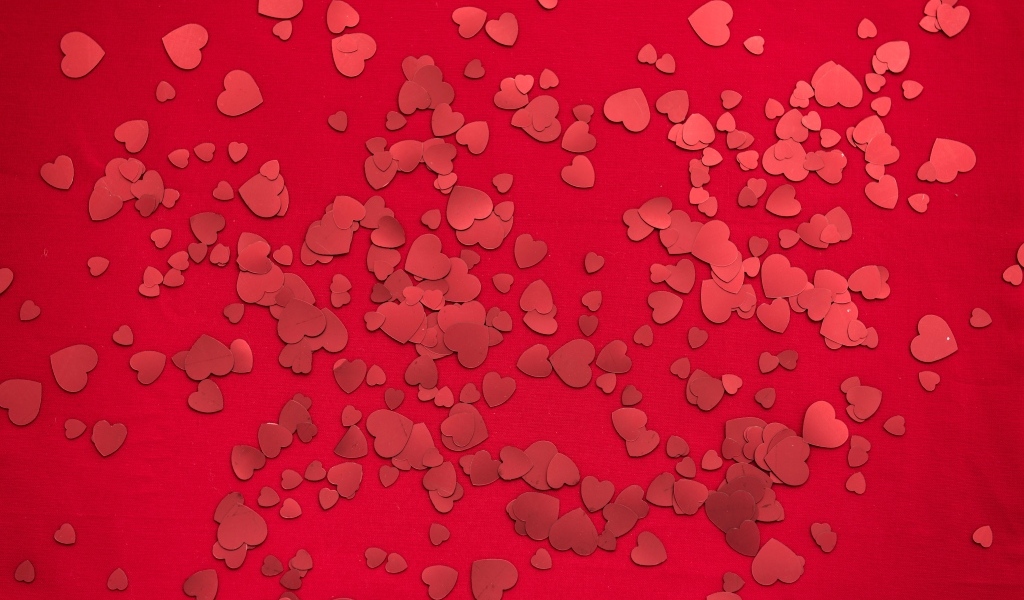 Маленькие бумажные сердечки на красном фоне