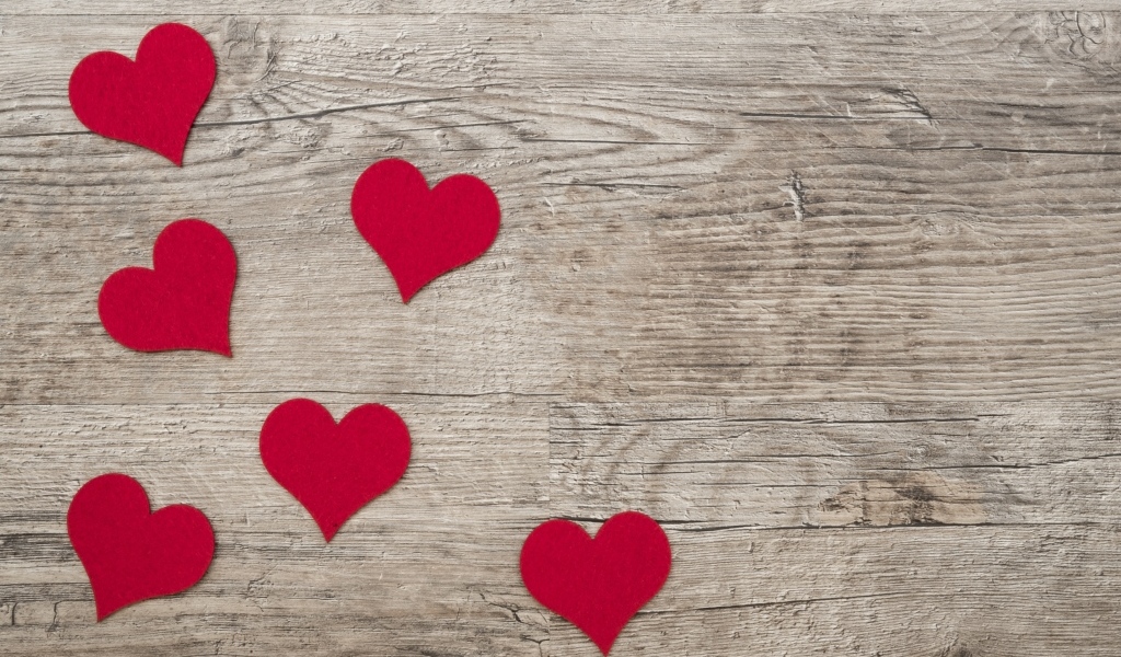 Маленькие красные сердечки на деревянном фоне