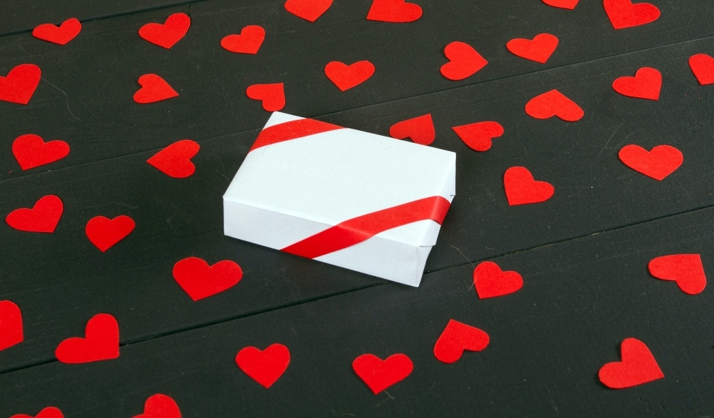 Белая коробка с маленькими бумажными сердечками на столе