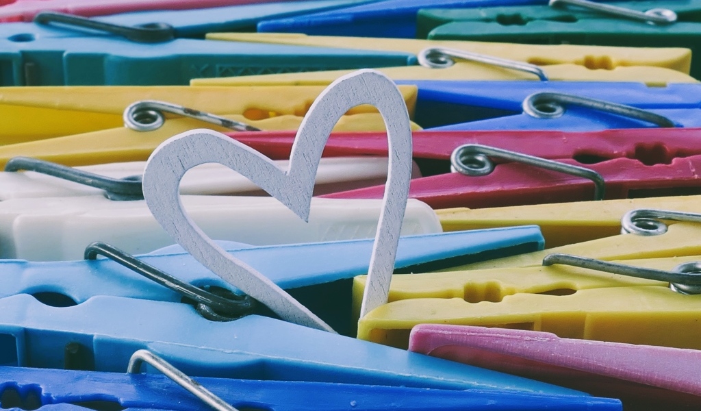 Белое деревянное сердце с разноцветными прищепками