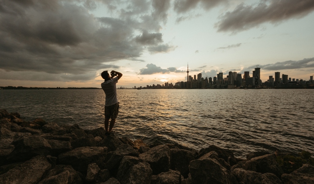 Мужчина делает фото города у моря