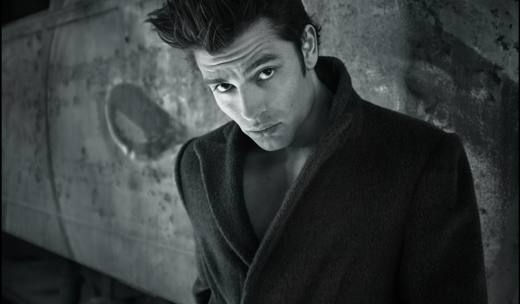 Красивый мужчина в черном пальто у стены