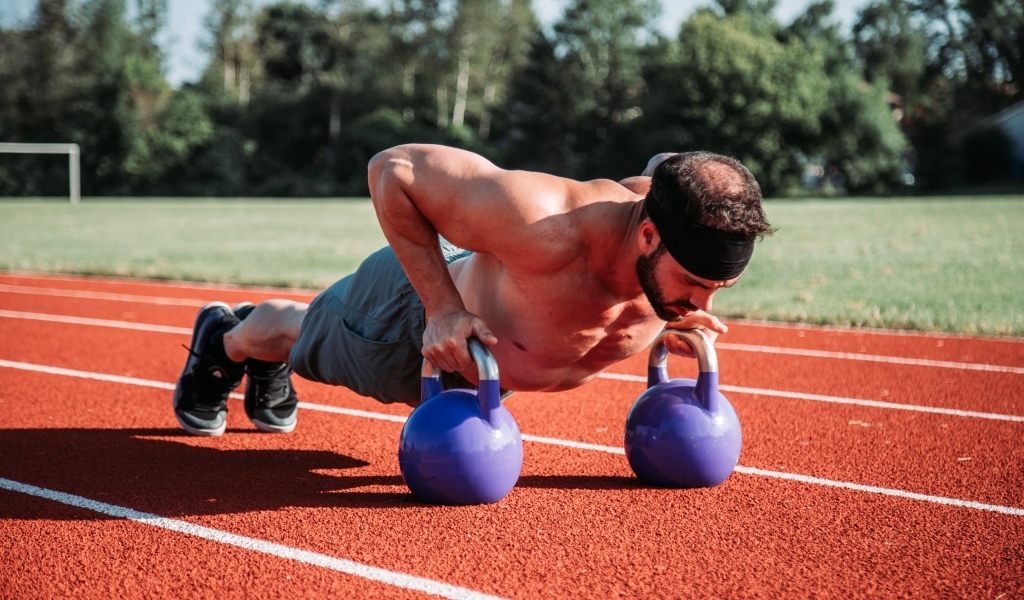 Мужчина спортсмен занимается с гирями