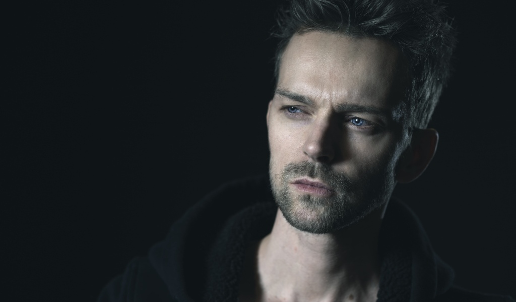 Серьезный голубоглазый мужчина на черном фоне