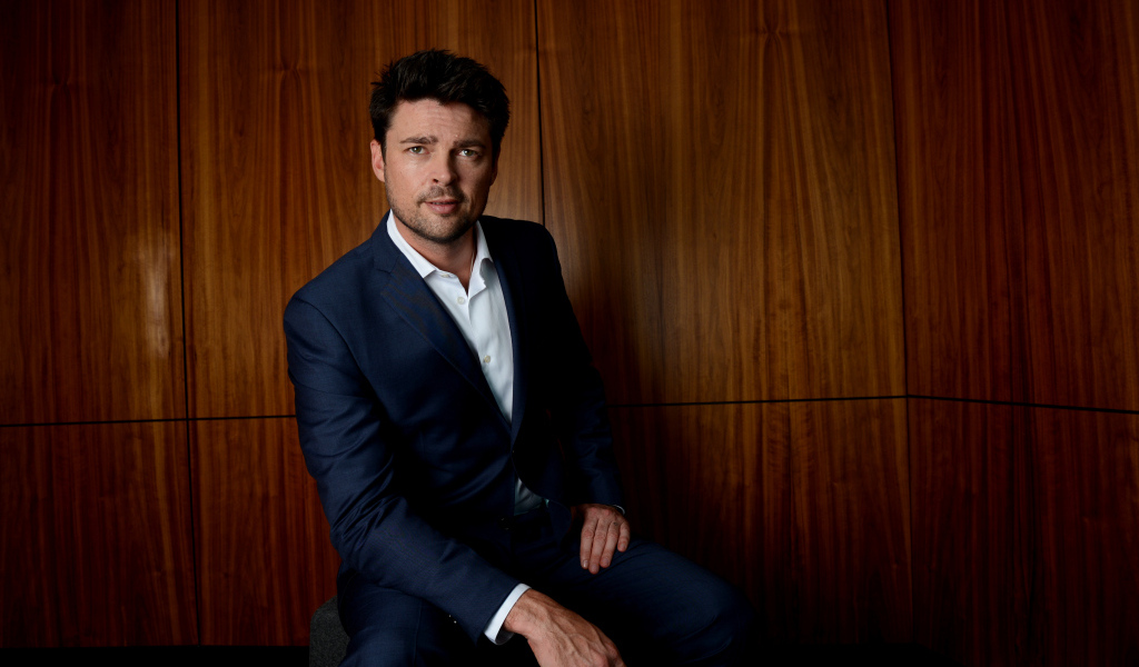 Актер Карл Урбан в костюме на фоне стены