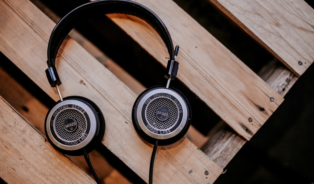 Старые наушники лежат на деревянной лавке