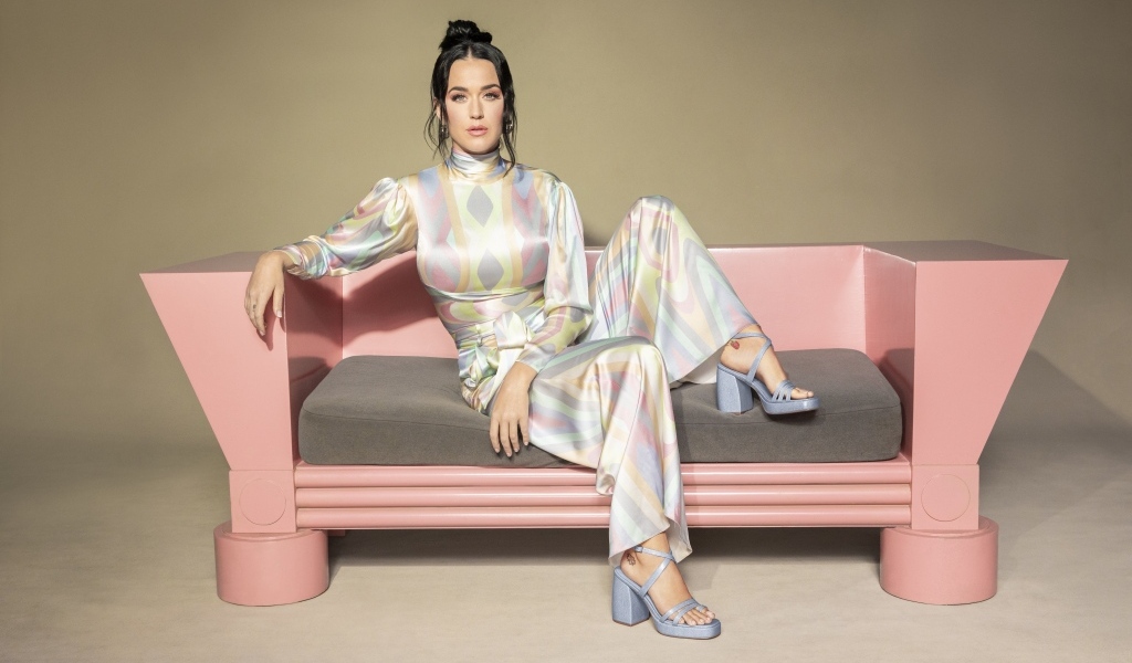 Певица Кэти Перри сидит на розовом диване