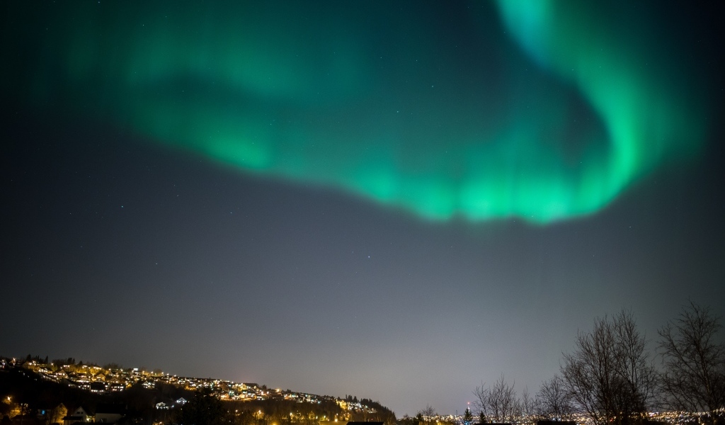 Зеленое полярное сияние в небе над ночным городом