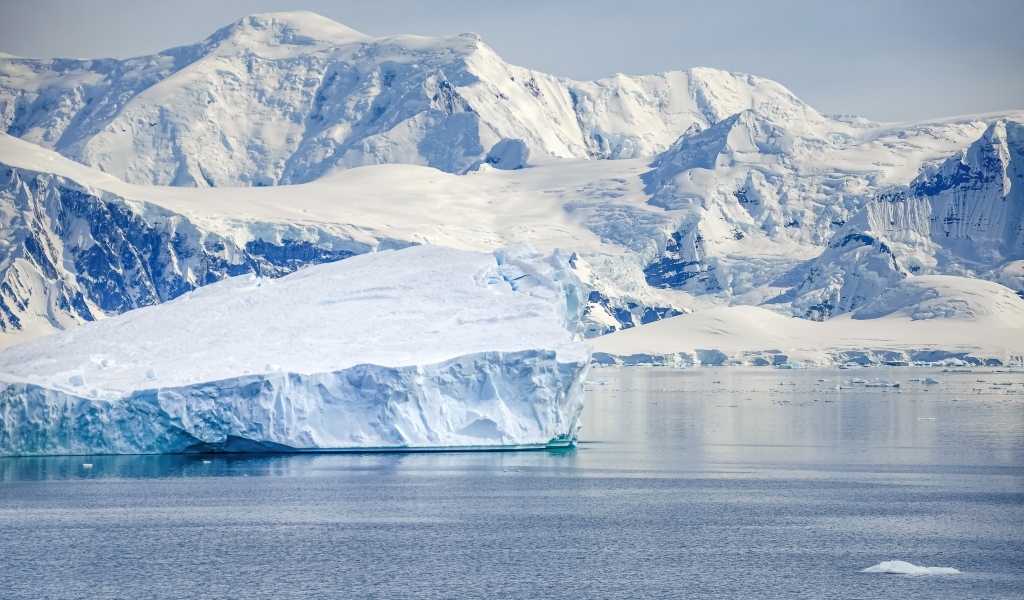 Большой айсберг у берега с заснеженными горами