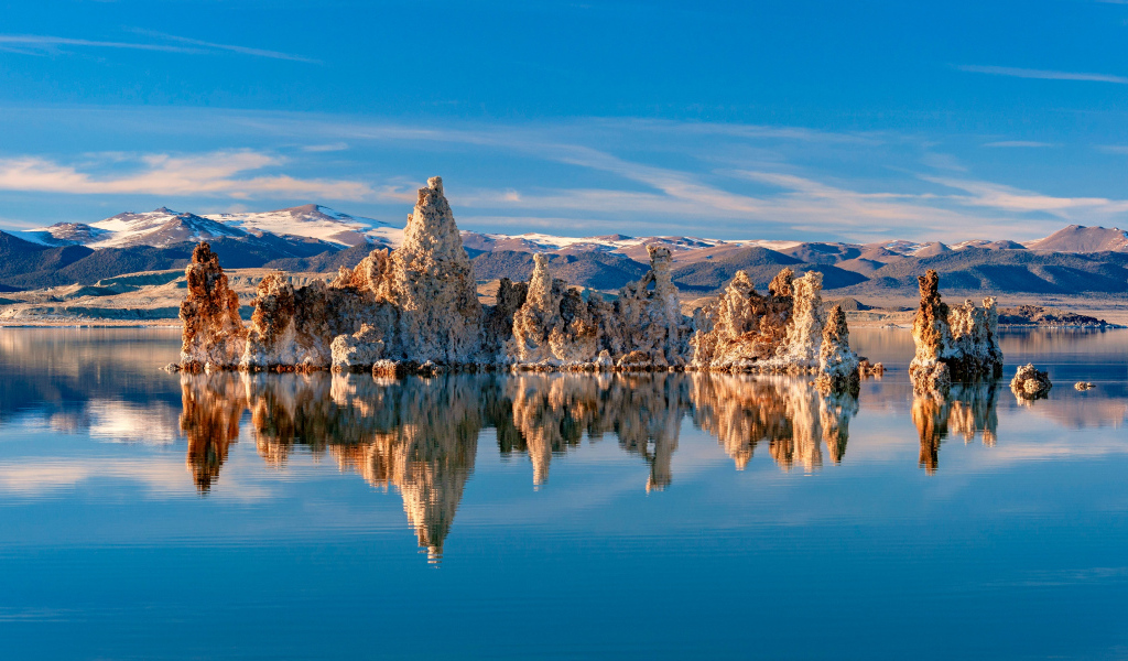 Острые скалы отражаются в тихой воде озера
