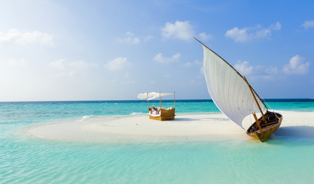 Лодка стоит на белом песке у голубого океана