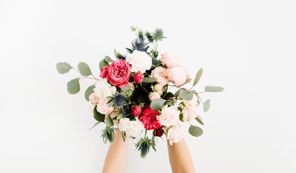 Букет цветов в руках у девушки на сером фоне