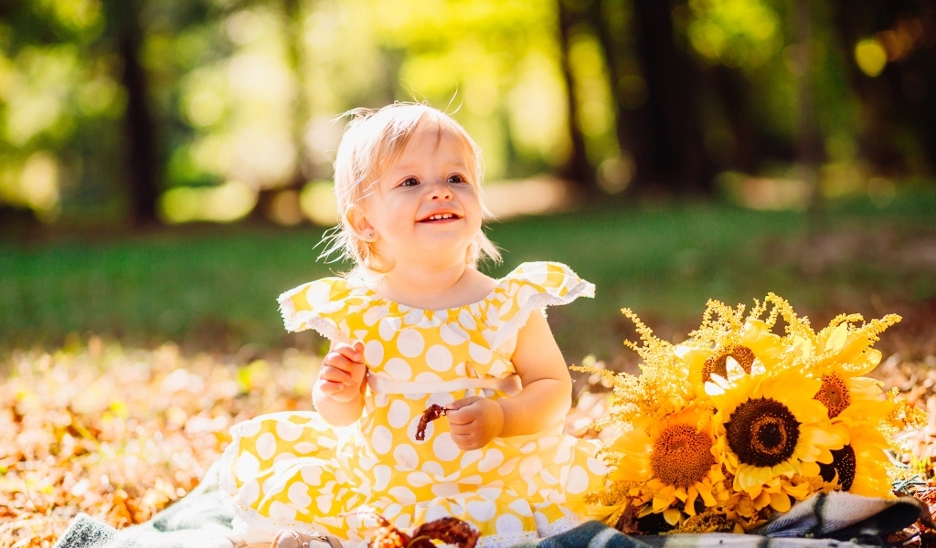 Малышка с цветами подсолнуха на траве