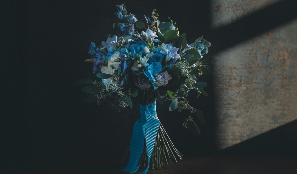 Красивый букет цветов с голубой лентой у стены